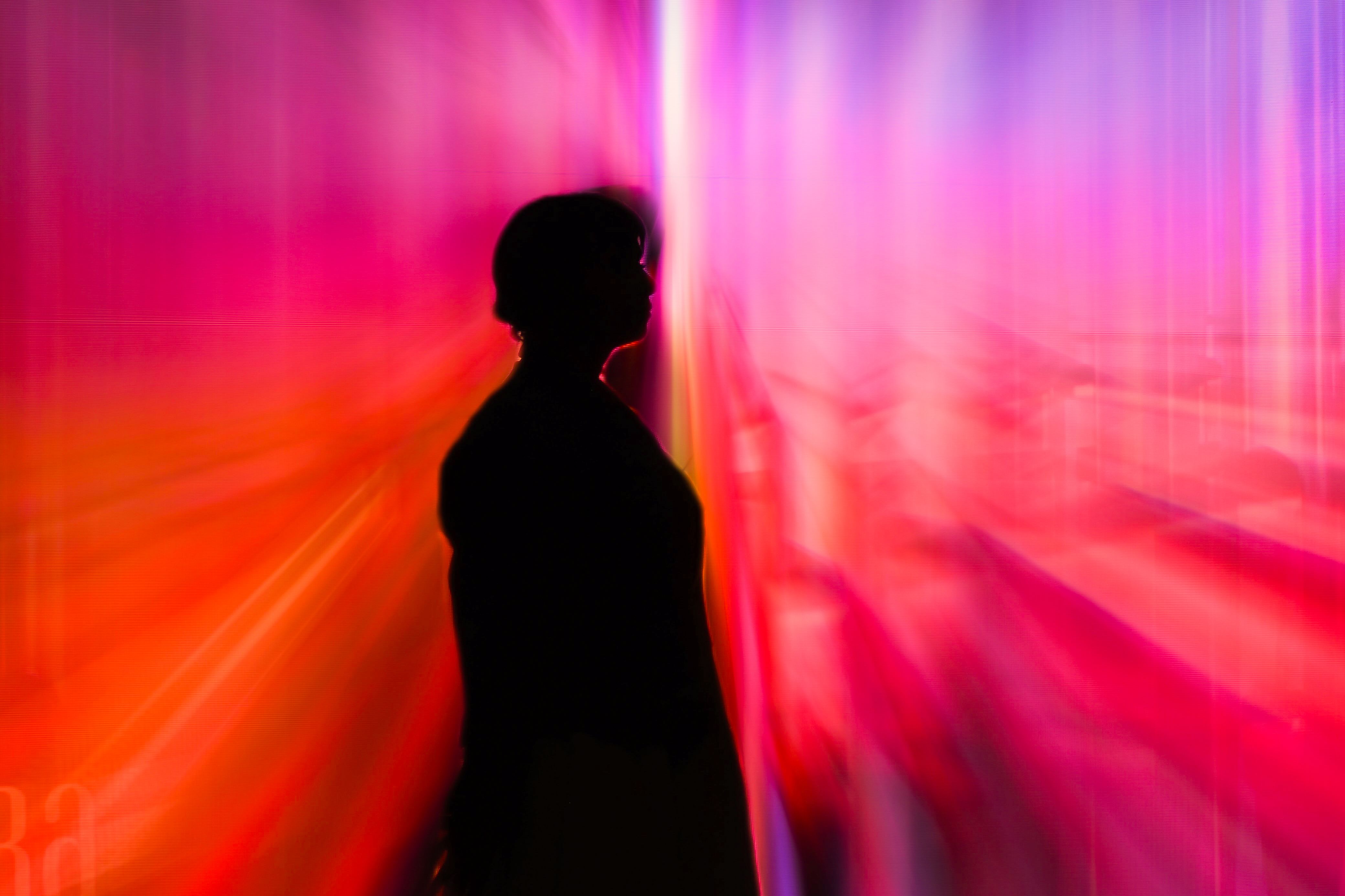 Silhouette of a person against a vivid abstract light installation in Moscow.
