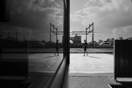 Black and white image of a man walking with reflection in Istanbul cityscape.