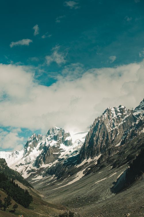 Free Breathtaking view of a snow-capped mountain range with summer skies in the background. Stock Photo