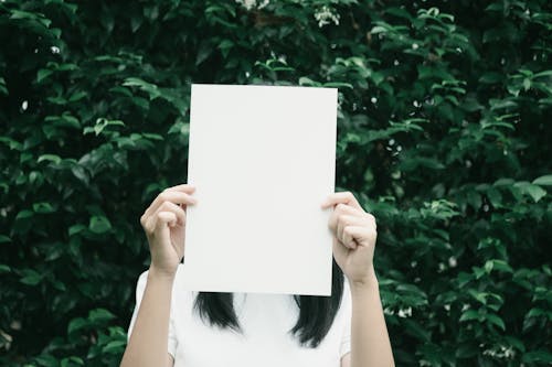 無料 葉の植物の横に白いプリンター用紙を保持している女性 写真素材