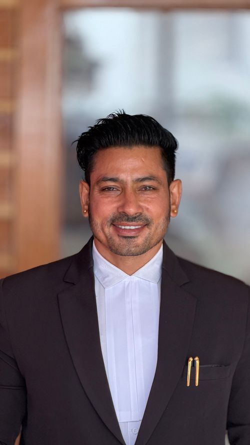 Free Smiling male professional in a suit standing indoors with soft background. Stock Photo