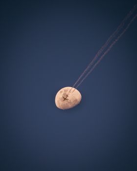 A striking capture of an airplane crossing in front of the moon against a clear, deep blue sky.