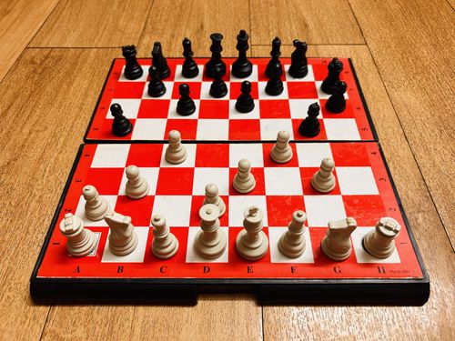 Free A unique red and white chess board with pieces on a wooden floor. Stock Photo