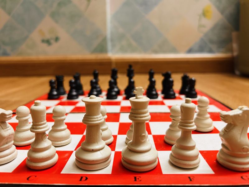 Close-up view of a chessboard with white and black chess pieces in focus.