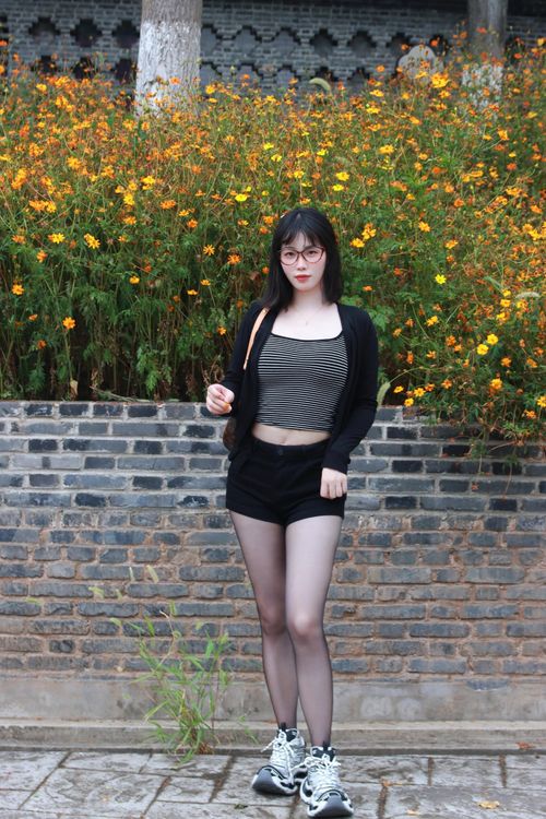 Free Portrait of a young woman standing outdoors in Nanjing, China, with vivid flowers in the backdrop. Stock Photo