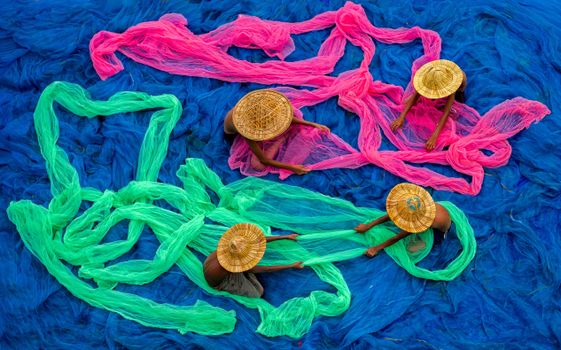 Aerial shot of people arranging colorful fishing nets, showcasing cultural and artistic expression.