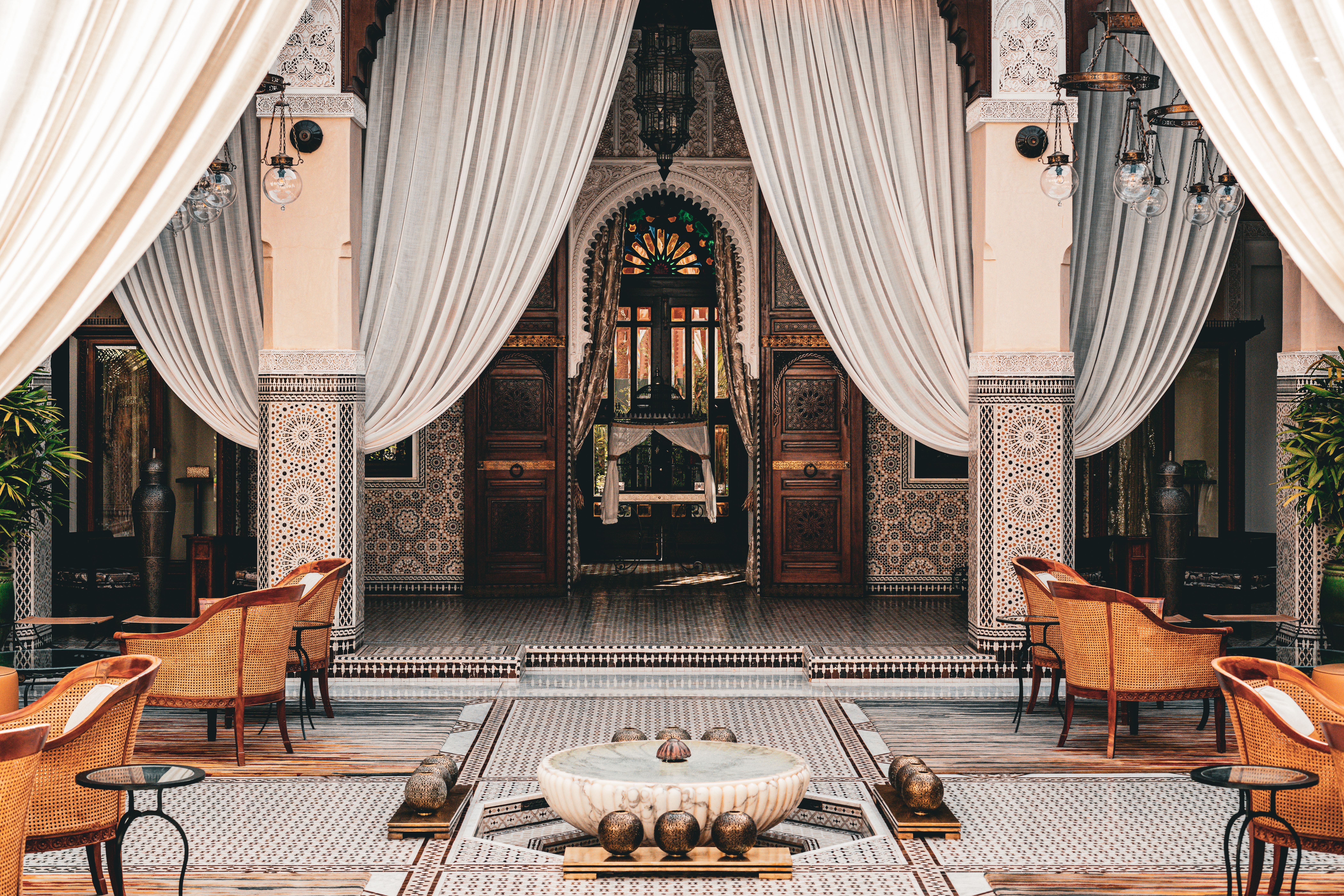 The tiled courtyard of a Marrakech riad, with drapes and a fountain