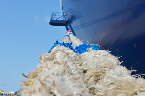 Free Detailed close-up of a heavy rope mooring line attached to a ship's hull with a clear blue sky background. Stock Photo