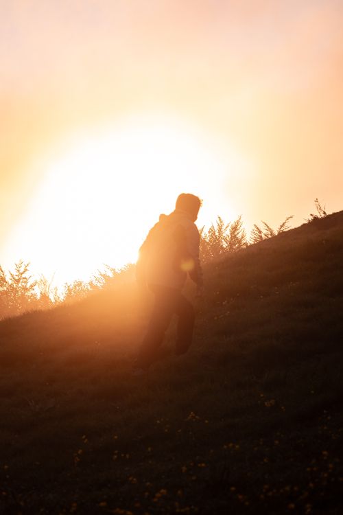 Free Silhouette of a hiker climbing a hill against a dramatic sunrise, capturing the essence of adventure and nature. Stock Photo
