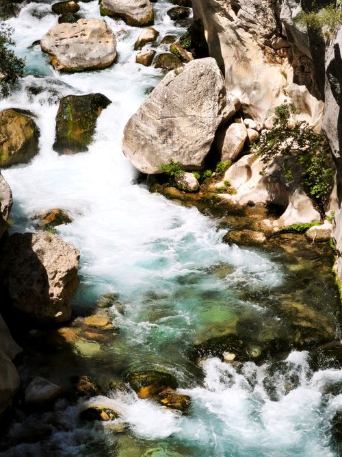 Free A serene river cascades through a rocky gorge, displaying vibrant turquoise waters and dynamic movement. Stock Photo