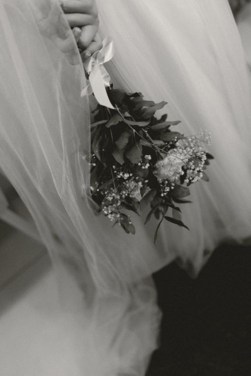 Free Close-up of a bride holding a bouquet, captured in black and white, highlighting elegance and romance. Stock Photo