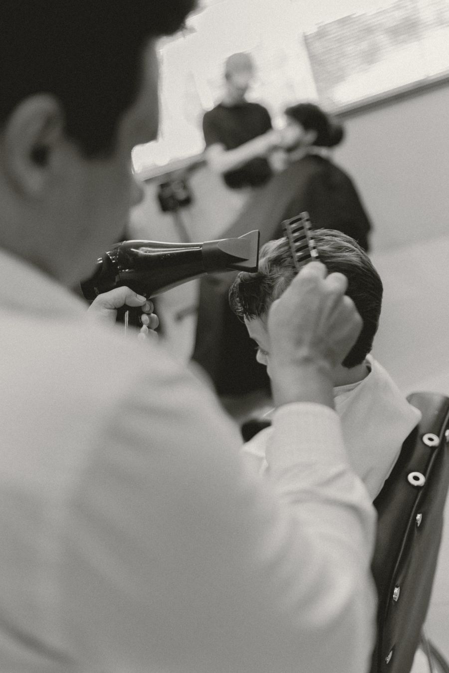 Estilista secando el cabello de un cliente, en blanco y negro