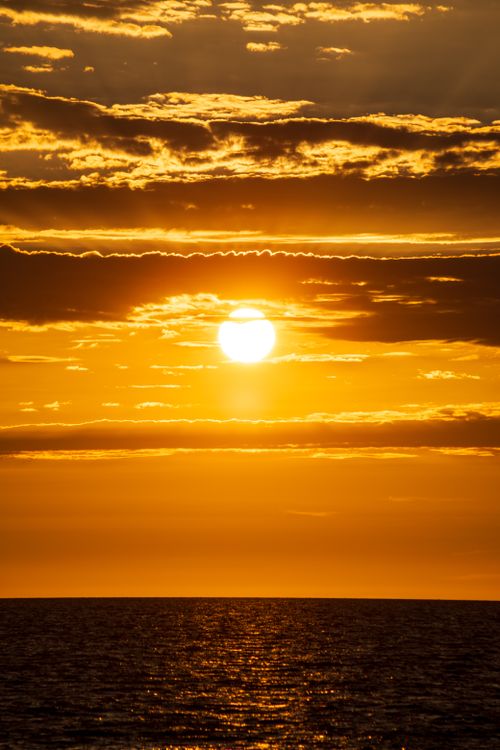 Free Beautiful golden sunset over the ocean with vibrant skies and calm waters, perfect for serene themes. Stock Photo