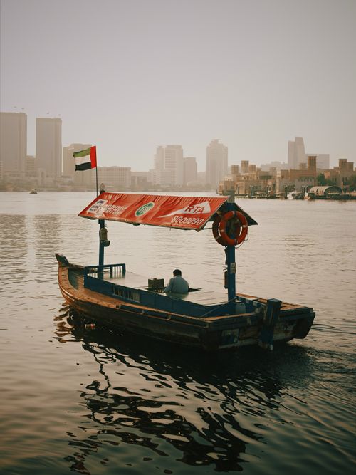 Free An abra boat carries passengers on Dubai Creek with city skyline in the background. Stock Photo