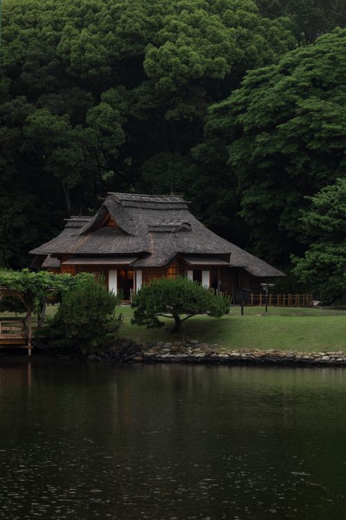 Free Scenic view of a traditional Japanese house by a lake in Tokyo, surrounded by lush greenery. Stock Photo