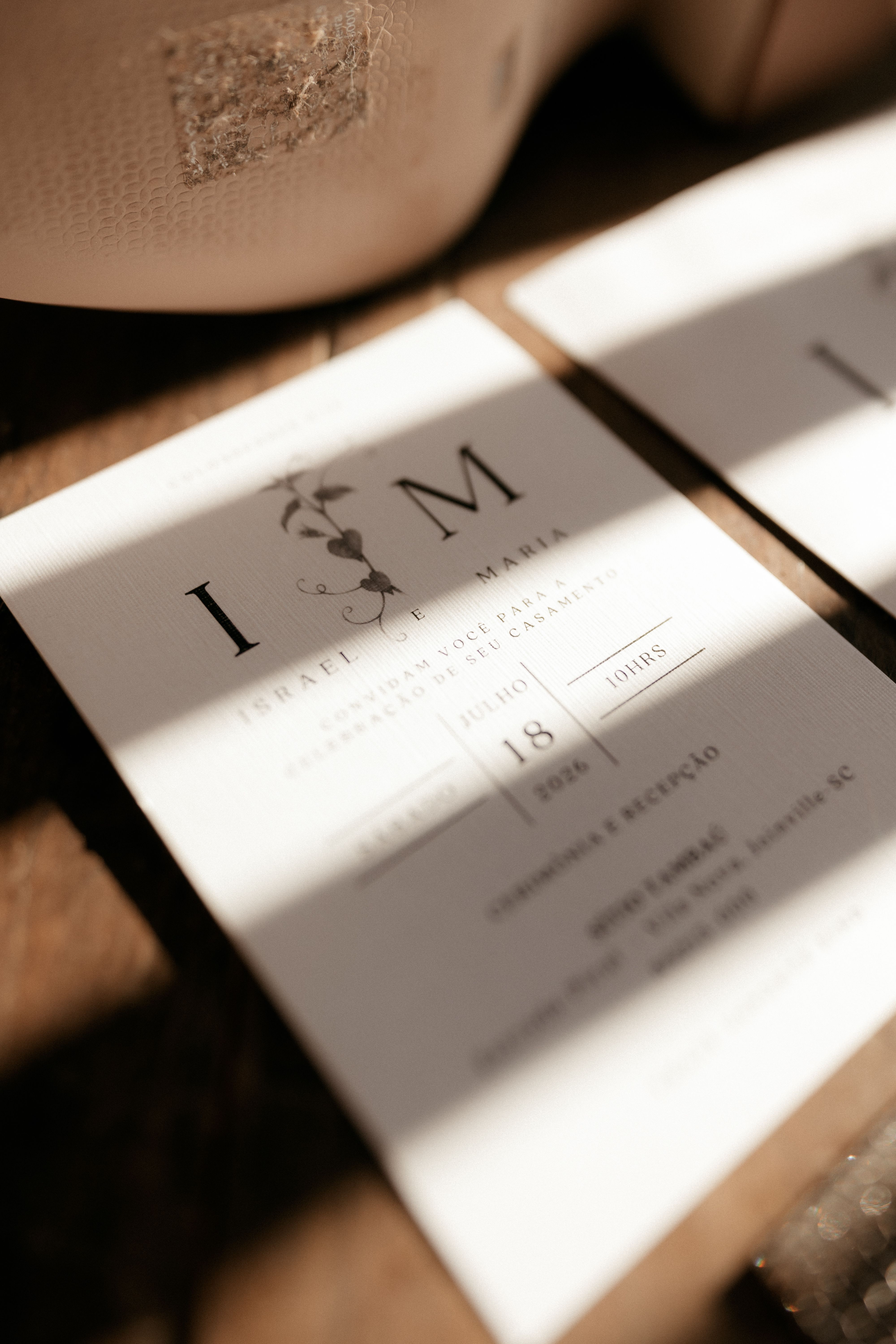 Close-up of a wedding invitation card with soft sunlight creating a warm, intimate atmosphere.