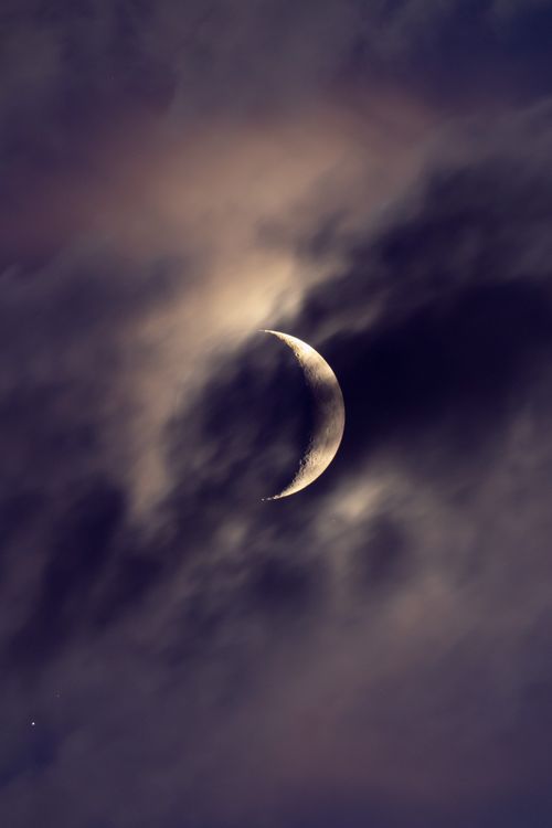 Free Crescent moon shining through the clouds at night, creating a mystical and serene atmosphere. Stock Photo