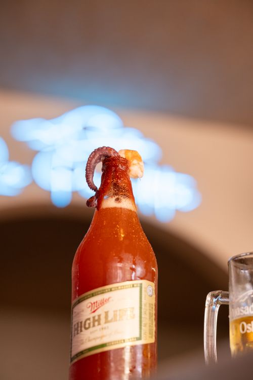 Free Innovative drink featuring an octopus tentacle garnish atop a beer bottle in a stylish bar setting. Stock Photo