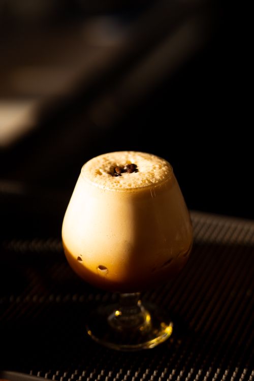 Free Close-up of a creamy coffee beverage in a glass cup, captured with artistic lighting. Stock Photo