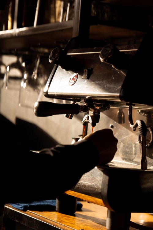 Free A barista preparing espresso using a professional coffee maker in a warm, atmospheric cafe setting. Stock Photo
