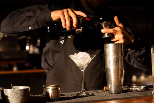 Free A bartender skillfully prepares a cocktail at a bar, showcasing professional mixing techniques. Stock Photo