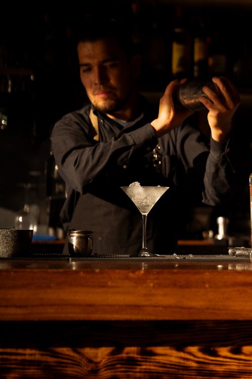 Free An experienced bartender expertly shakes a cocktail in a cozy bar setting, creating a sophisticated drink with finesse. Stock Photo