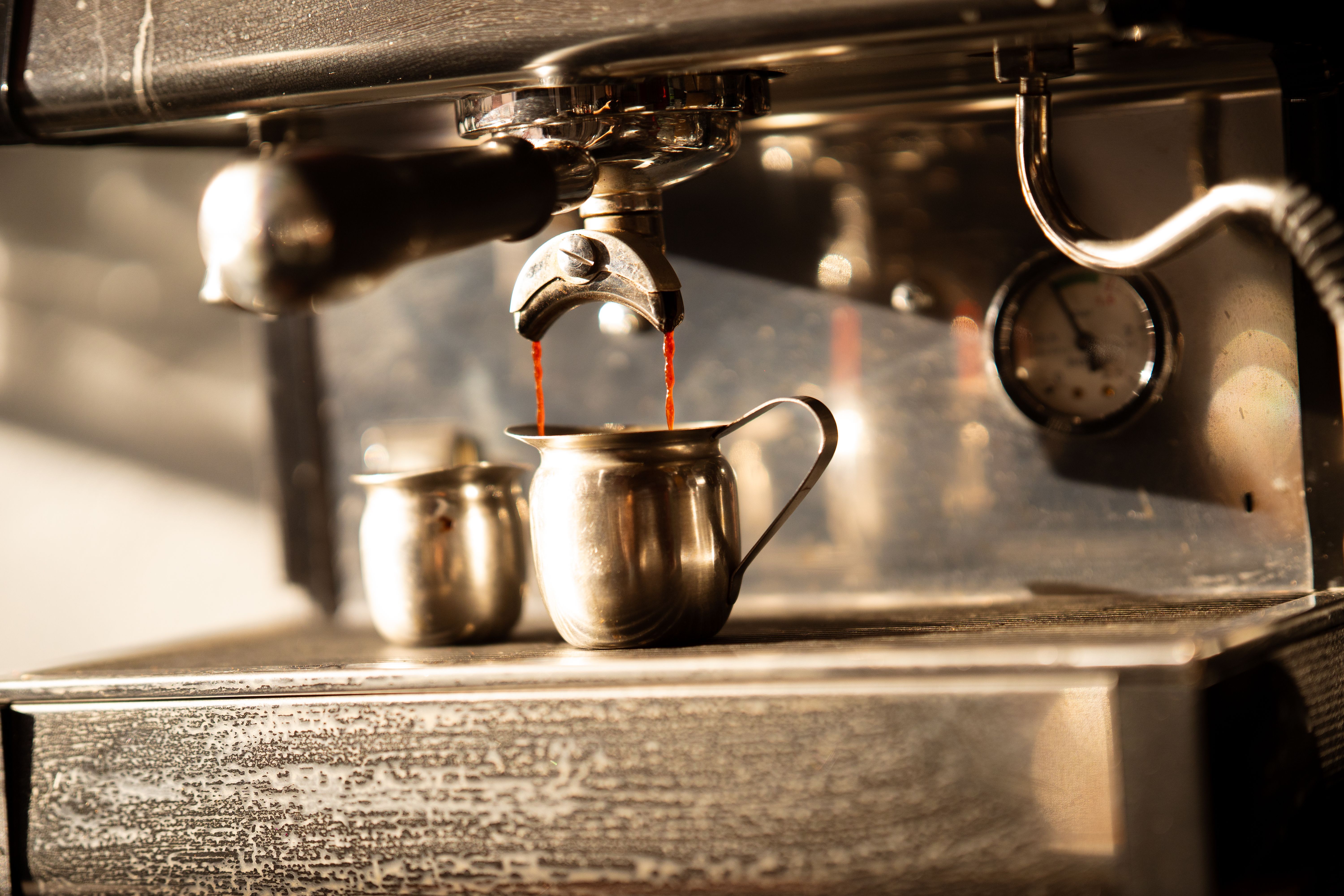 Close-up of an espresso machine making coffee with steaming jets in a cozy café atmosphere.