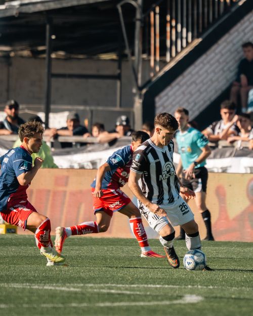 Free Midfield soccer players in action during a competitive match with a lively crowd in the background. Stock Photo