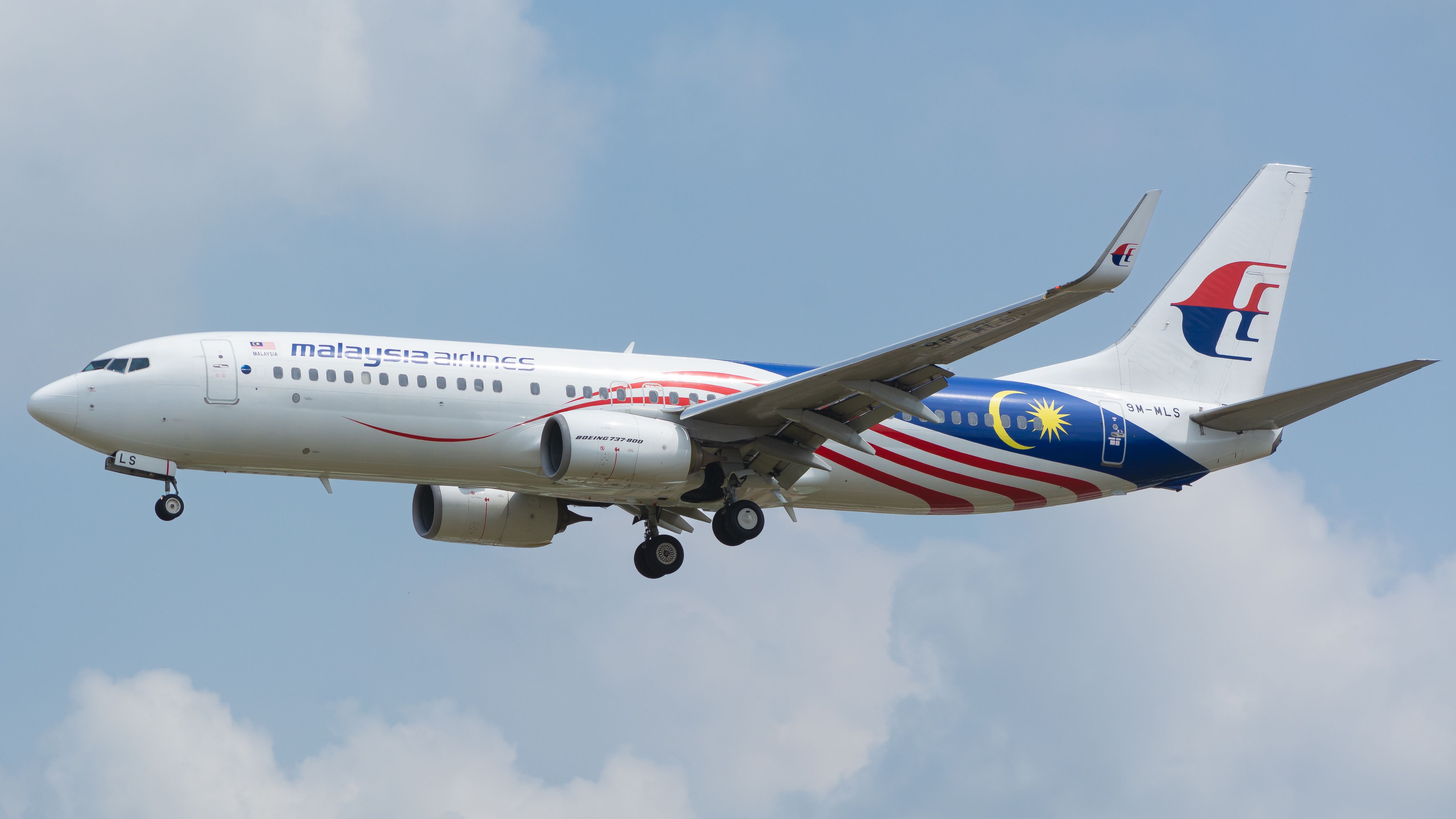 Malaysia Airlines Boeing 737 mid-flight against a cloudy sky background.