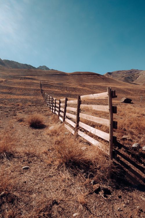 Free A wooden fence stretching across the dry, rocky terrain of Mendoza, Argentina under a clear sky. Stock Photo