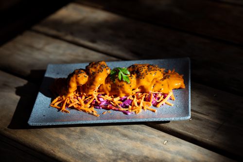 Free A gourmet dish with carrot, cabbage, and sauce, beautifully plated on a rustic wooden table. Stock Photo