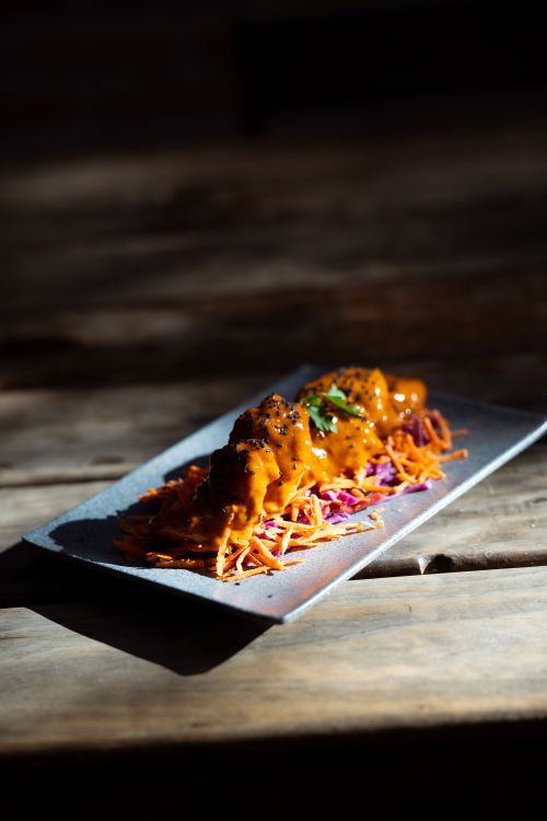 Free A gourmet dish featuring spicy sauce over slaw on a rustic wooden table. Stock Photo