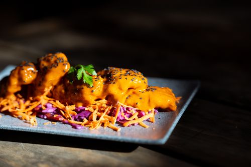 Free Close-up of a gourmet dish with bright sauce on a slate plate garnished with vegetables. Stock Photo