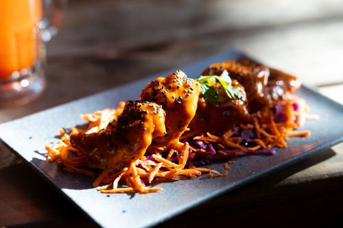 Free Delicious spicy dumplings with sesame seeds served on an artistic plate, garnished with fresh vegetables. Stock Photo