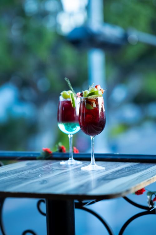 Free Refreshing craft cocktails with fruit garnish on an outdoor table, perfect for summer evenings. Stock Photo