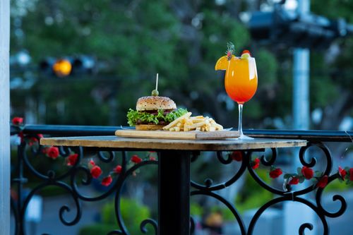 Free A burger and fries with a vibrant cocktail on a decorated outdoor table. Stock Photo