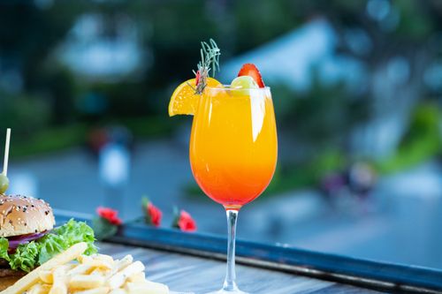 Free A vibrant summer cocktail garnished with fruits, paired with a burger and fries, perfect for outdoor dining. Stock Photo