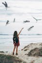 开普敦海滩上，一名妇女向海鸥伸手，营造出宁静自然的景象
