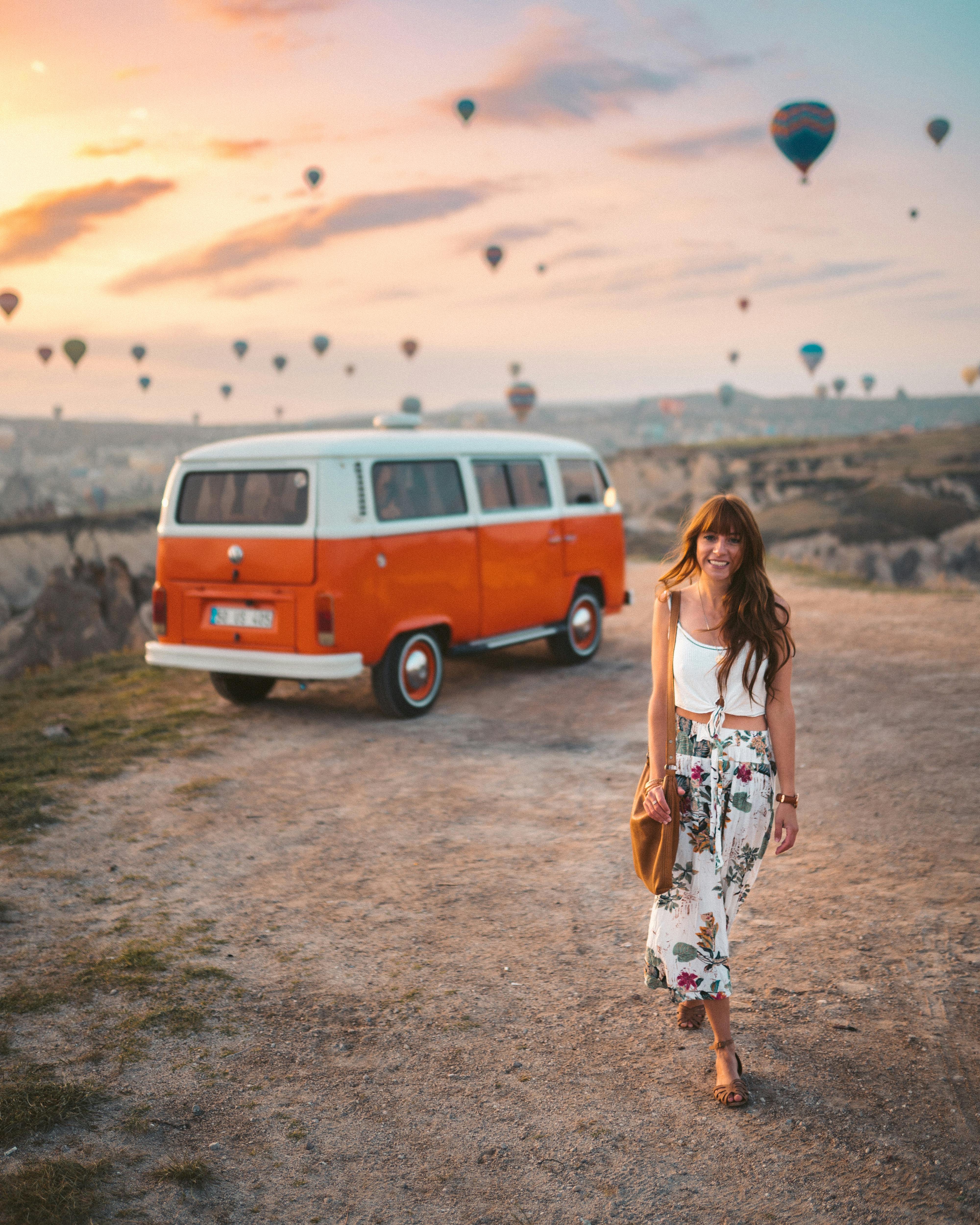 woman in white top and floral skirt near vehicle