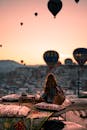在土耳其卡帕多西亚的日出时分，一名女子凝视着热气球