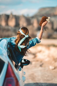 一位穿着牛仔布的女人从车窗探出身来，享受着穿越土耳其卡帕多西亚的公路旅行