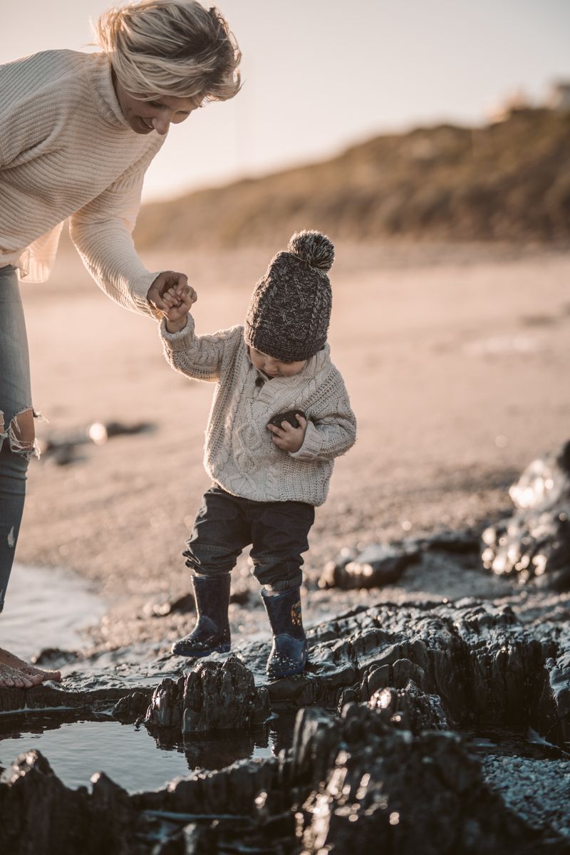 A tender moment between a mother and child walking on the beach, exploring nature.