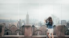 一名女子在洛克菲勒中心用双筒望远镜观看纽约市天际线