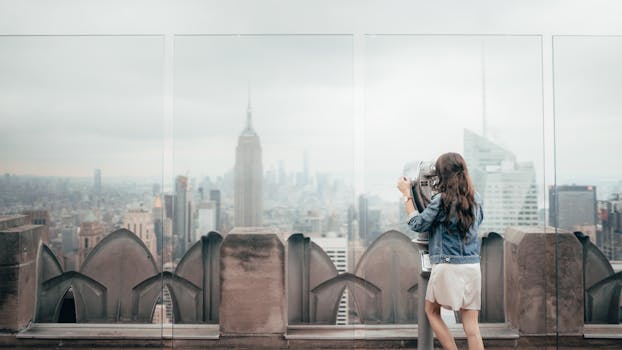 Woman viewing New York City skyline from Rockefeller Center with binoculars. by Taryn Elliott