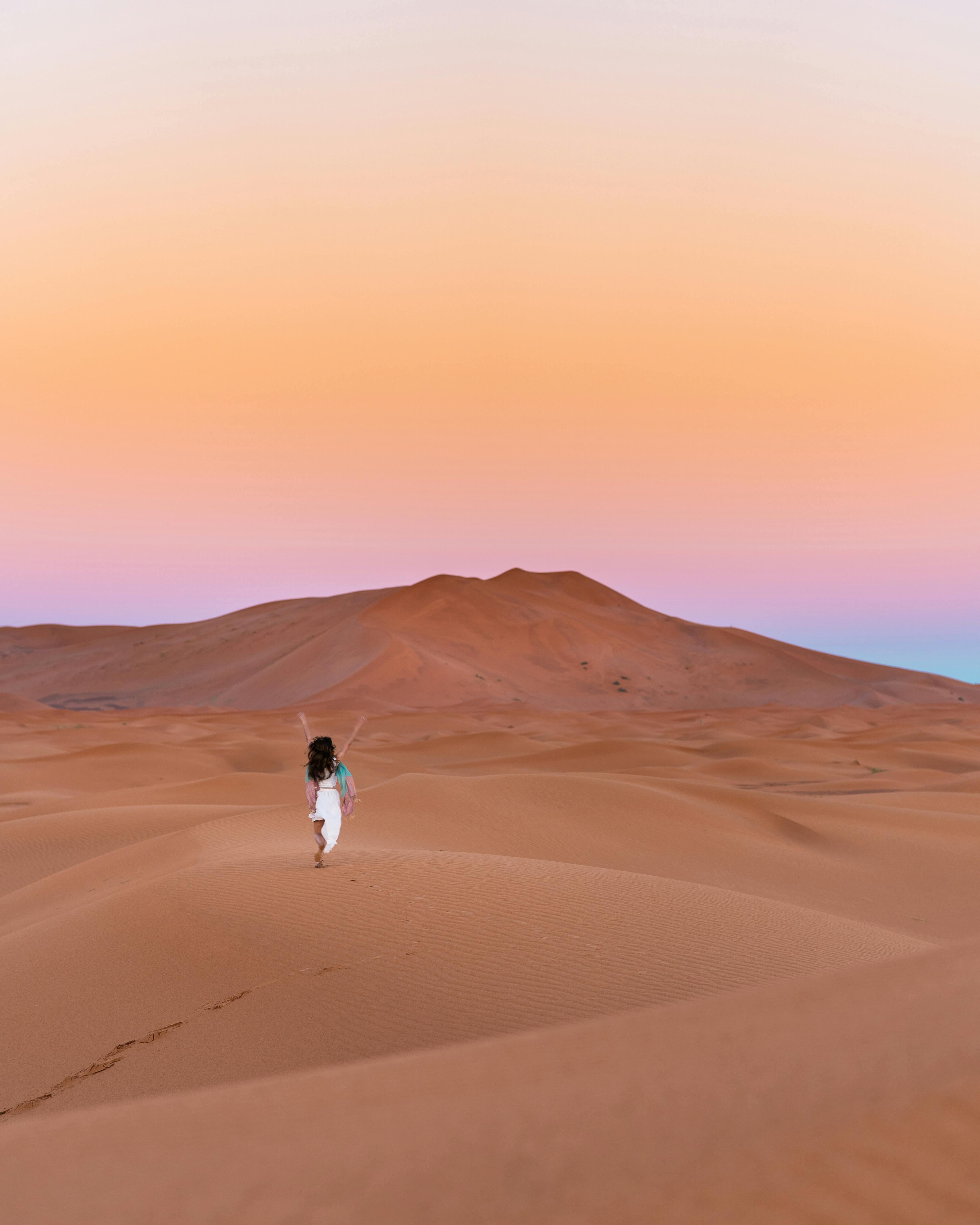 photo of person walking on dessert