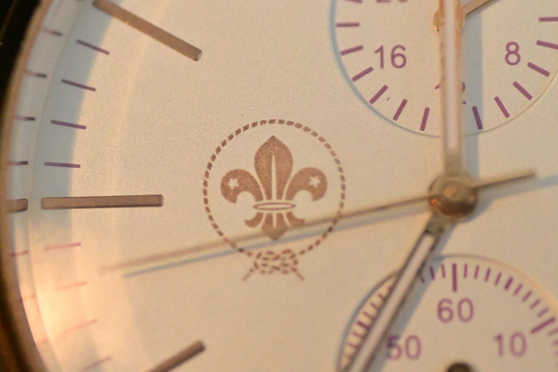 Detailed view of a classic analog watch face featuring a fleur-de-lis design.