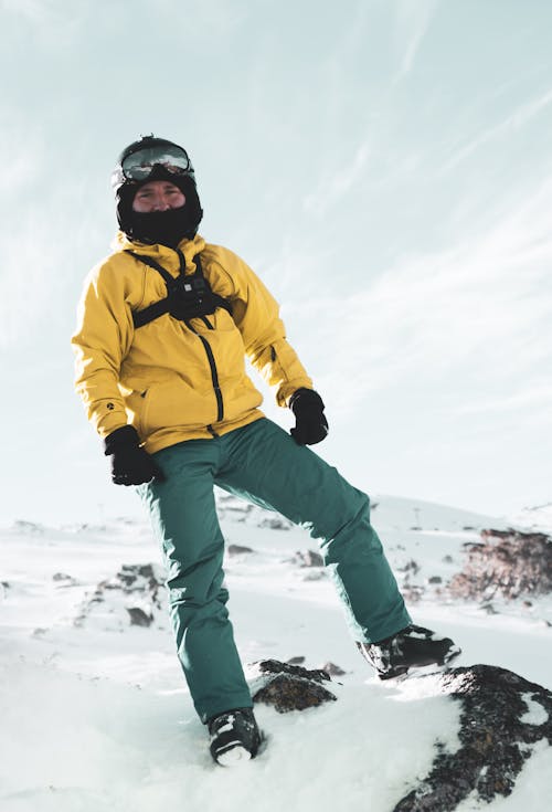 Man In Yellow Jacket Standing On Snow Covered Ground