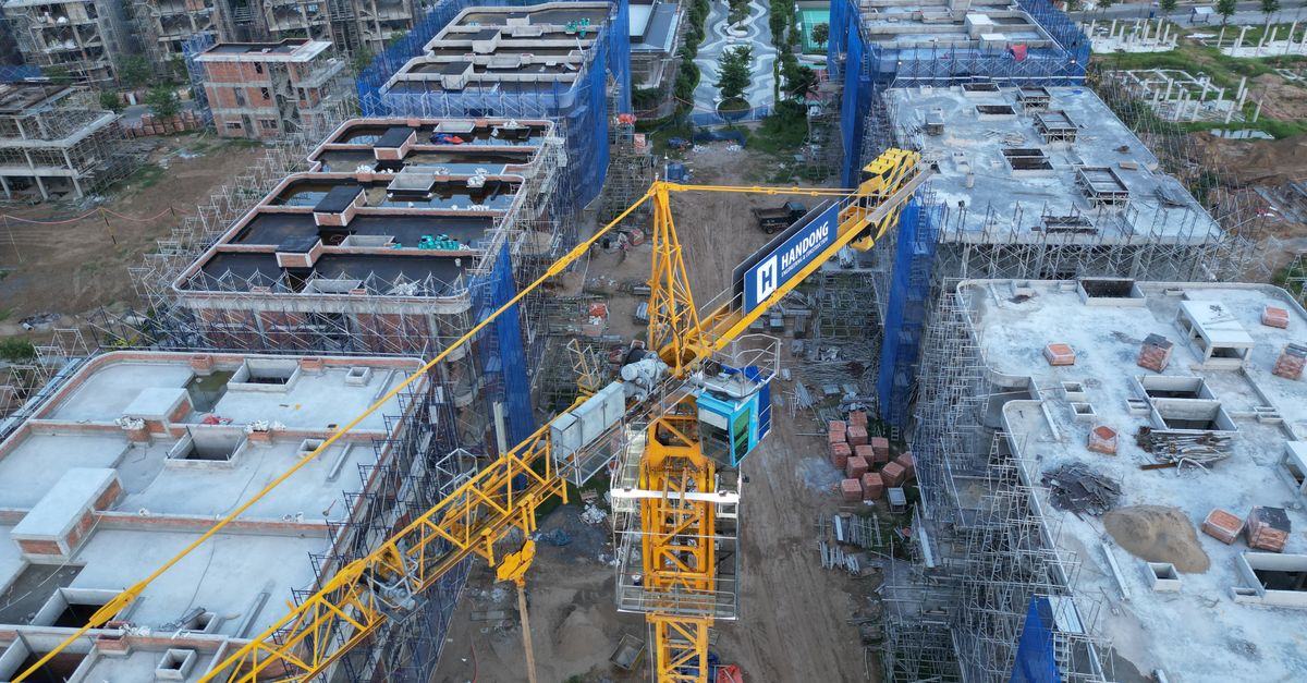 Aerial shot of a construction site featuring a prominent yellow tower crane amidst multiple buildings under construction.
