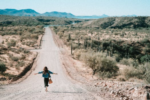 A woman walks freely down a winding desert road in Arizona, embracing adventure.