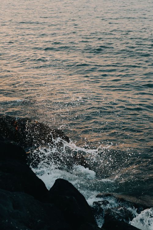 Free Dramatic seaside view of waves splashing against rocks at sunset in Samsun, Türkiye. Stock Photo
